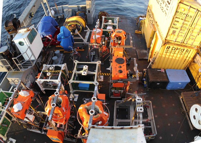 A ship deck crowded with orange oceanographic equipment