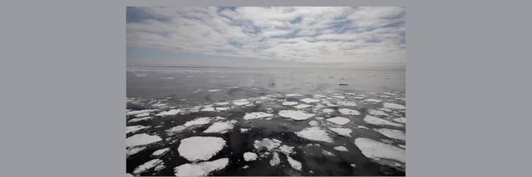 Photo of cloudy sky and dark ocean with sea ice floating