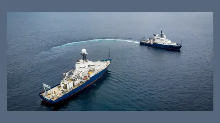 Two ships with one crossing in front of the other in open ocean 