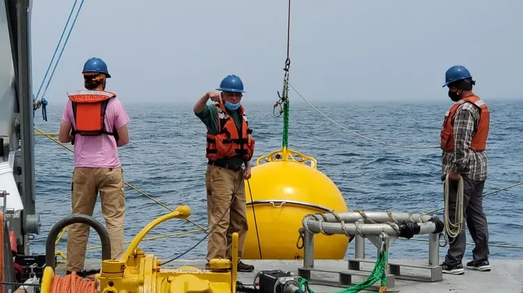 People working on the aft end of a shipping deploying equipment