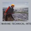 Person leaning on a ship's rail wearing a life jacket and hard hat with the background of a gray sea